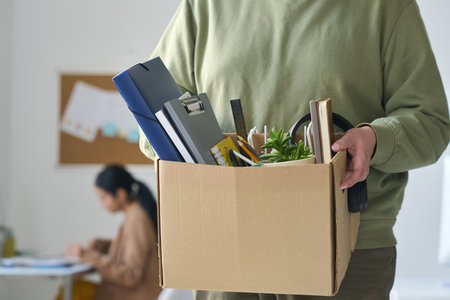Close-up of businessman holding box with office stuff while moving to a new officeの写真素材