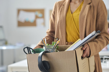 Close-up of businesswoman packing things in box while moving in new officeの写真素材