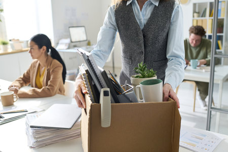 Close-up of businesswoman packing her things in box and leaving her workplace in officeの写真素材