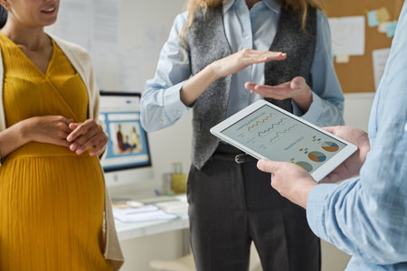 Business people using tablet pc with financial graphs and discussing report in teamの写真素材