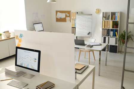 Modern office with computers with graphs on monitors on workplaces of business peopleの写真素材