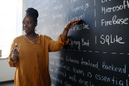 African American teacher pointing at blackboard and teaching IT lesson to studentsの写真素材