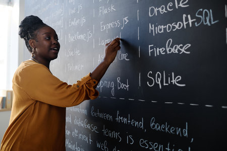 African American woman writing on blackboard, she teaching IT lesson at schoolの写真素材
