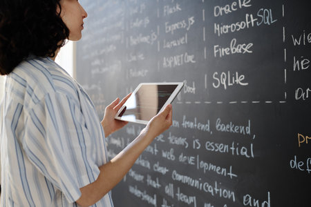 Student standing in front of blackboard and reading information, she using tablet pc at lessonの写真素材
