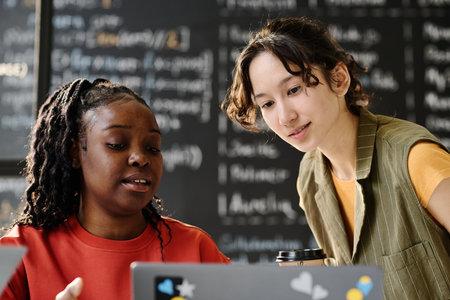 African American teacher using laptop to explain material to student during lesson in the classroomの写真素材
