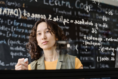 Student writing codes on blackboard during IT lesson in the classroomの写真素材