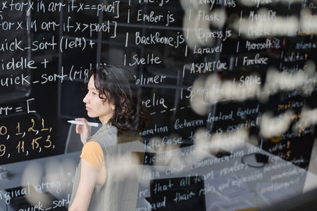 Student writing codes on blackboard during IT lesson in the classroomの写真素材