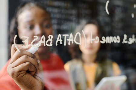 African American teacher writing on blackboard and teaching IT to student during lessonの写真素材