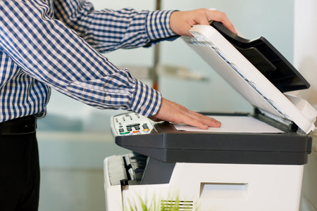 Close-up of unrecognizable copying place employee putting file in scanner to make copy in officeの写真素材