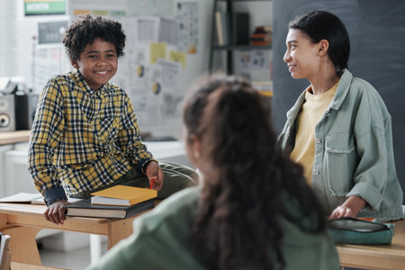 African American school children sitting at desk and talking to each other after lesson in the classroomの写真素材