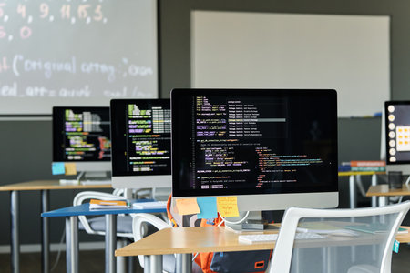 Computers on desks with codes on monitors for studying IT in schoolの写真素材