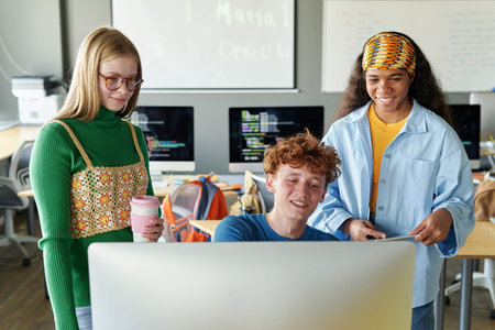 Group of students sitting in front of computer monitor and working with software in team in the classroomの写真素材