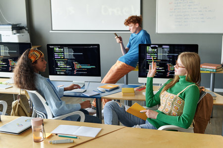 Group of students sitting at desk with computers during IT lesson in the classroomの写真素材