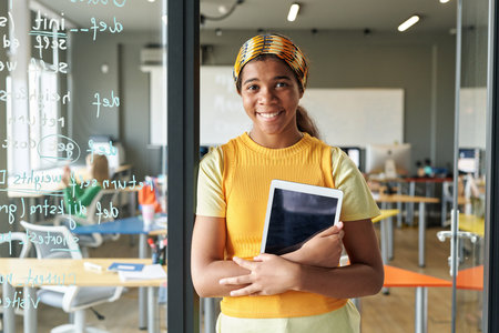 Portrait of African American student with digital tablet smiling at camera while learning IT at schoolの写真素材