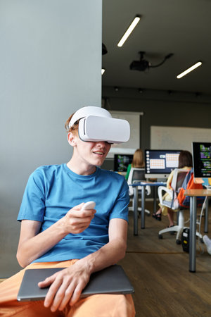 Vertical image of student using VR glasses at lesson in the classroomの写真素材