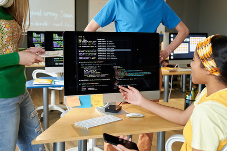 Group of students discussing computer codes on computer in team during IT lessonの写真素材