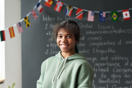 Portrait of African American schoolgirl smiling at camera while standing in the classroomの写真素材