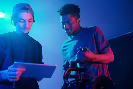 Director using digital tablet while discussing content with photographer in studioの写真素材