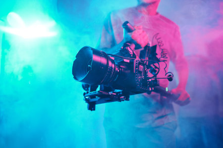 Cameraman shooting content with professional camera among smoke in photo studioの写真素材