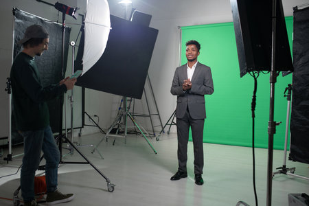 Filming process of TV program with presenter standing against the green background and telling the newsの写真素材
