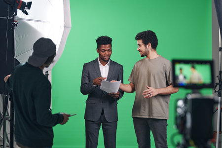 African American presenter discussing script with director while they standing in professional studioの写真素材