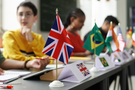Group of international students sitting at table with flags and having lesson at schoolの写真素材
