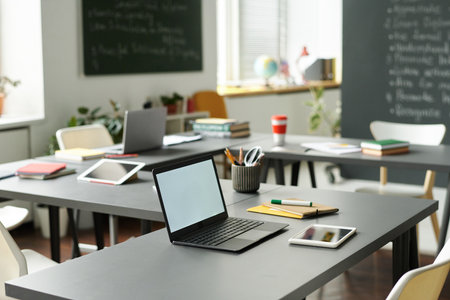 Laptop for online work on desk in empty classroom at schoolの写真素材
