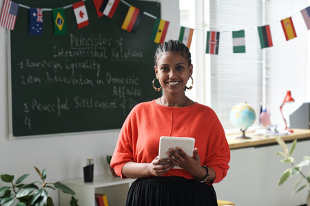 Portrait of African American woman smiling at camera while standing in the classroom and using tablet pcの写真素材