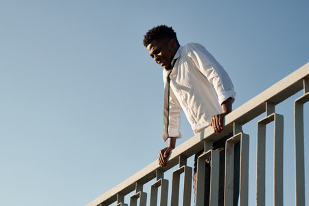 Low angle view of African American man in depression standing on the bridge and trying to jumpの写真素材