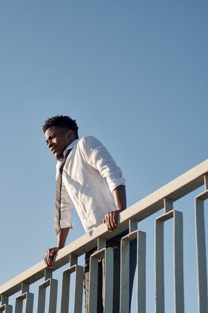 Vertical image of African American man standing on the rails of bridge and trying to jumpの写真素材