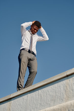 Vertical image of depressed young man having problems he standing on the roof and trying to commit suicideの写真素材