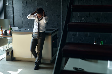 African American young guy worrying about his addiction, he staying alone in the room with alcohol drinksの写真素材