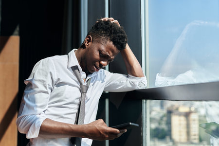 African American man reading bad message on his smartphone and looking very worriedの写真素材