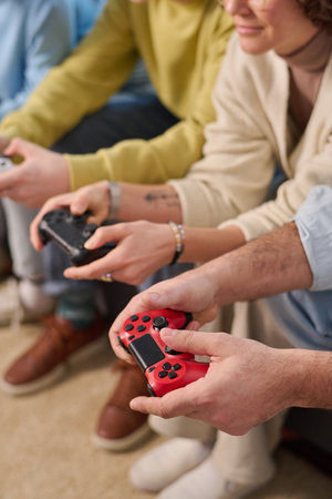 Vertical image of family of four playing video game with joysticks while sitting on sofa at homeの写真素材