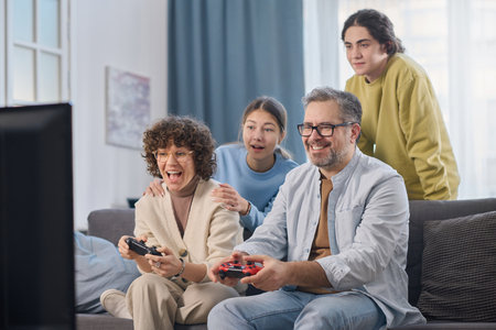 Family of four having fun together at home while sitting on sofa in the living roomの写真素材