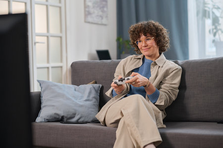 Young woman sitting on sofa in the living room and playing video gameの写真素材