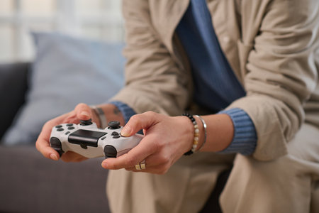Close-up of woman using joystick to play game while sitting on sofa at homeの写真素材