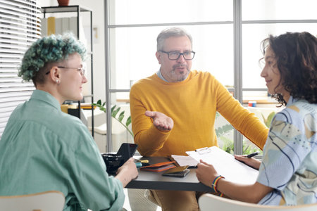 Professional consultant talking to young lesbian girls during meeting in officeの写真素材