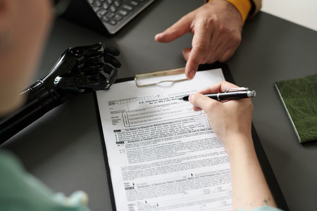 High angle view of woman with disability filing insurance documents during meeting with consultant in officeの写真素材