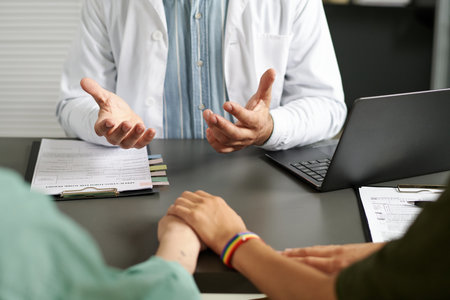 Close-up of professional doctor talking to lesbian couple while they having meeting in officeの写真素材