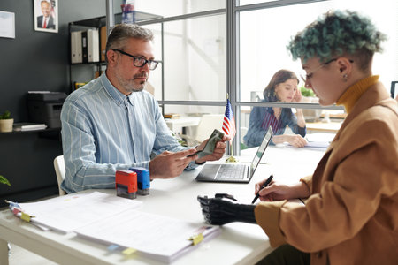 Woman with disability having meeting with manager in office while giving documents for visaの写真素材