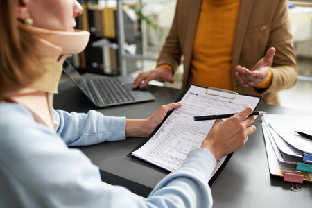 Woman with injury signing contract with insurance agent during their meeting in officeの写真素材
