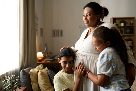 African American pregnant mother with her daughters spending time at homeの写真素材