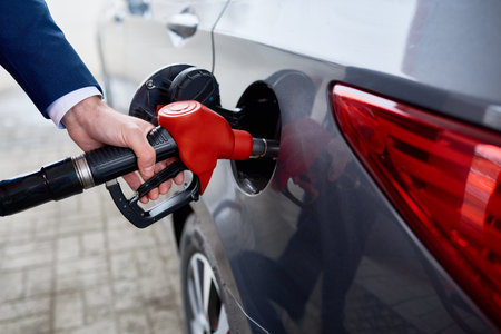 Closeup of unrecognizable businessman refueling gas tank of black luxury carの写真素材