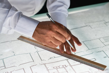 Close up of unrecognizable architect drawing plans at workstation in office, copy spaceの写真素材