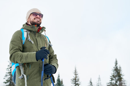 Cheerful brave handsome climber in sunglasses conquering new heights while hiking alone in mountainsの写真素材