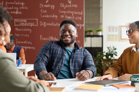 Portrait of smiling African American student enjoying group discussion at table in college classroom. copy spaceの写真素材