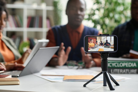 Closeup of college professor recording video lecture via smartphone with group of students copy spaceの写真素材
