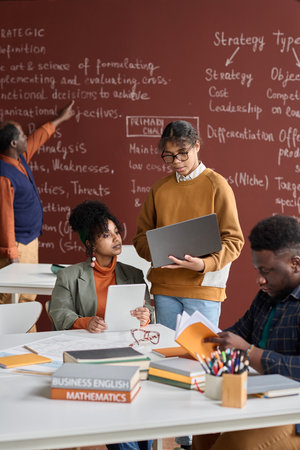 Vertical portrait of African American college students doing group study in college classroom with blackboard in backgroundの写真素材