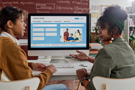 Side view of two Black students discussing career opportunities in college classroomの写真素材